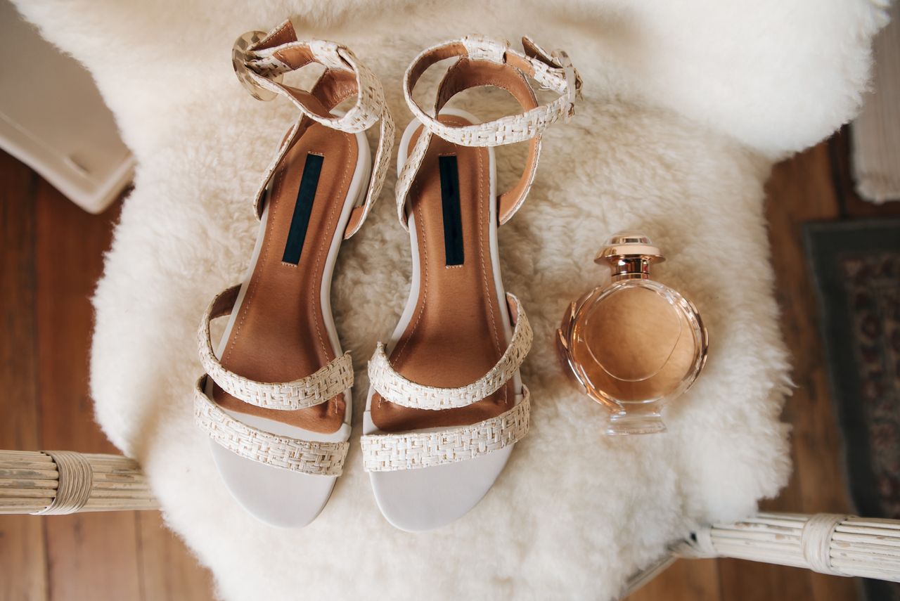 services-03 Stylish white sandals paired with a chic perfume bottle in a cozy setting for a fashion-forward still life shot.